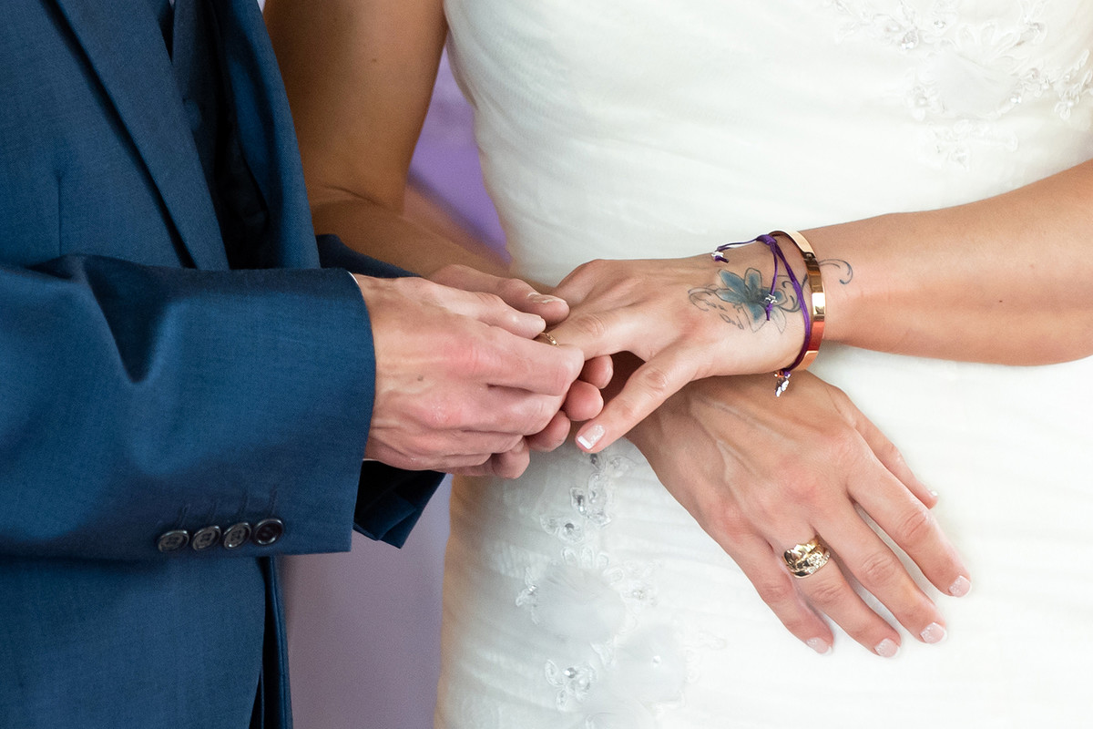 Tight crop groom placing ring on bride's finger